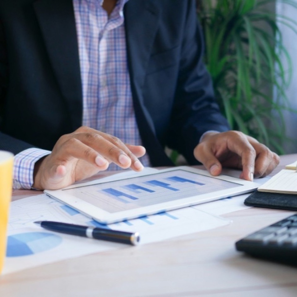 Professional reviewing analytics charts on a tablet at a desk